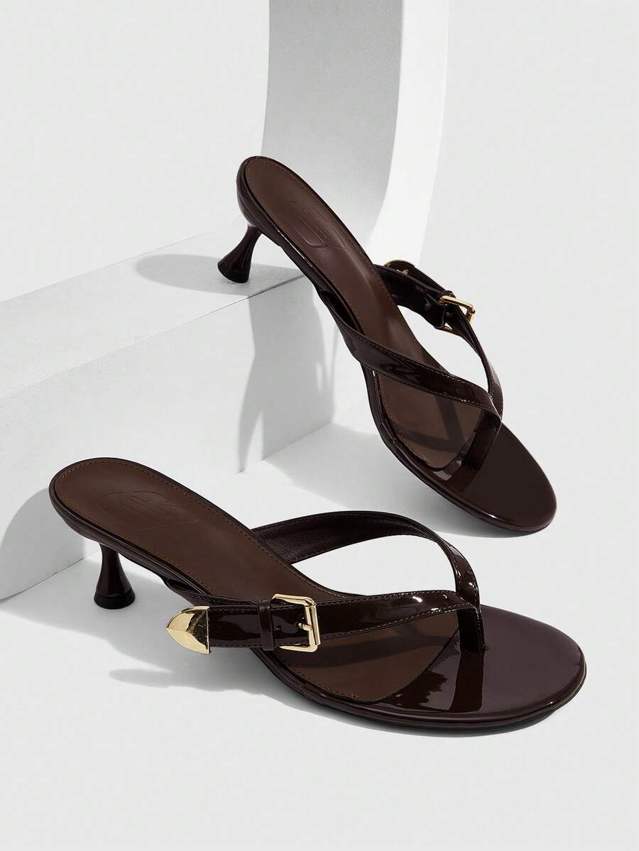 Women's patent leather heeled sandals featuring a toe post strap with metal buckle and mid pyramid heel.