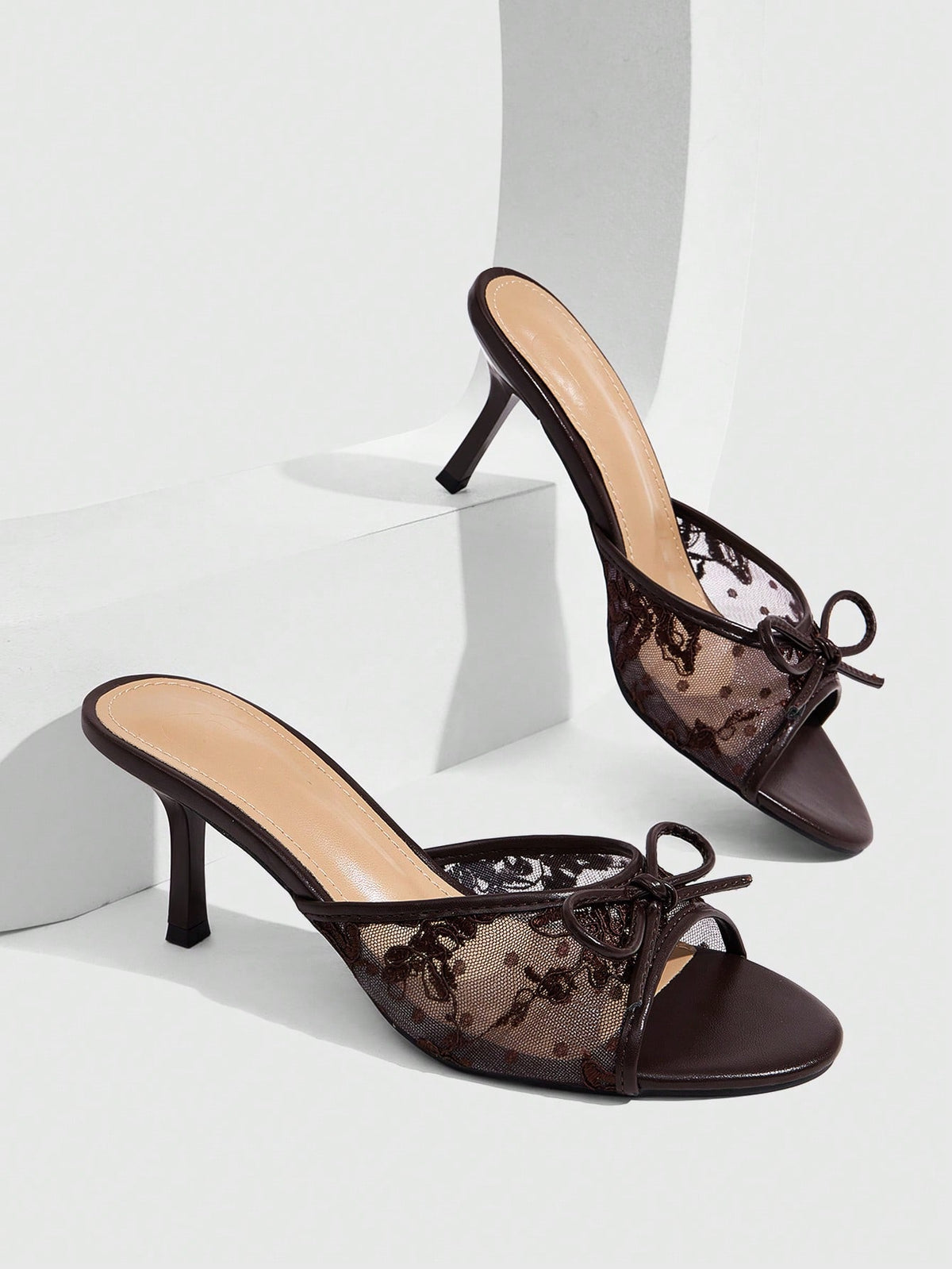 Open toe high heel slide sandals featuring lace details and a bow accent on the upper strap.
