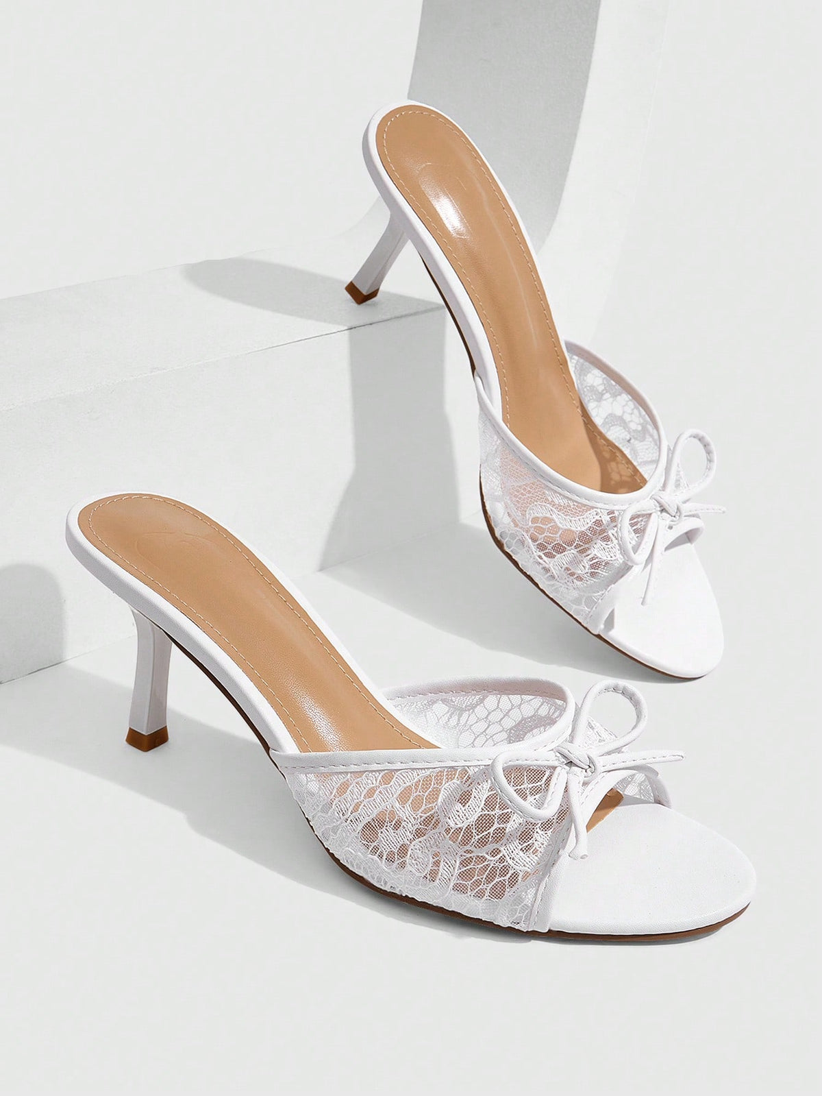 Open toe high heel slide sandals featuring lace details and a bow accent on the upper strap.