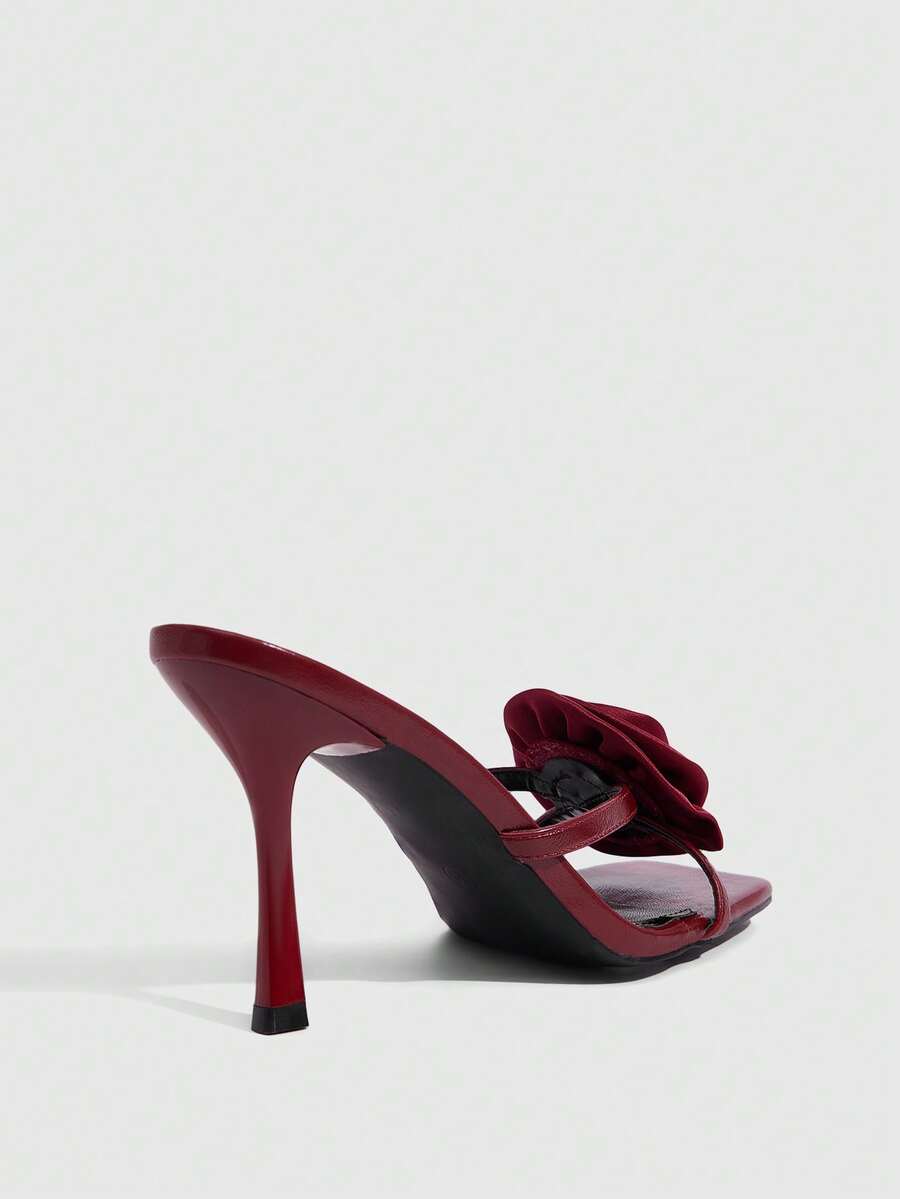 Women's open toe satin slip-on heeled sandals featuring an elegant flower accent and high stiletto heel.