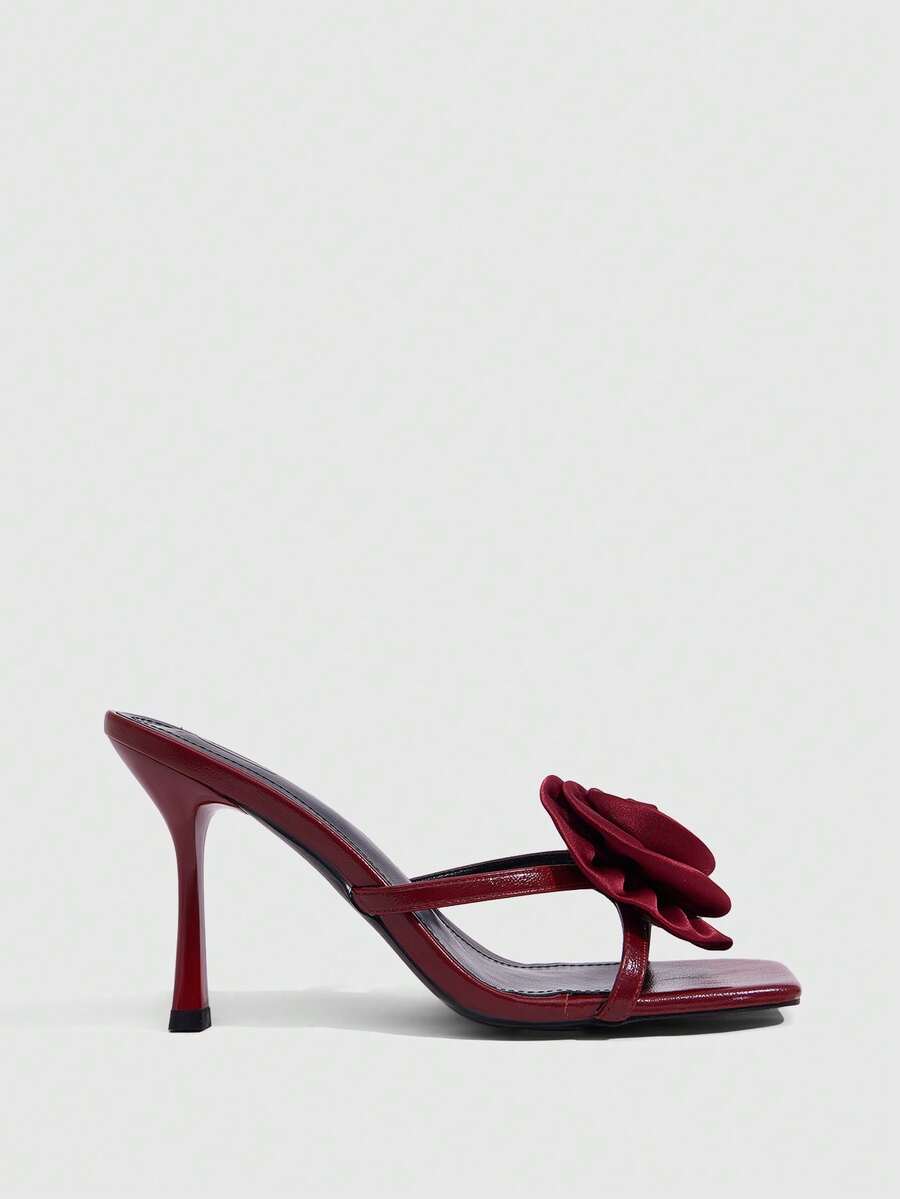 Women's open toe satin slip-on heeled sandals featuring an elegant flower accent and high stiletto heel.