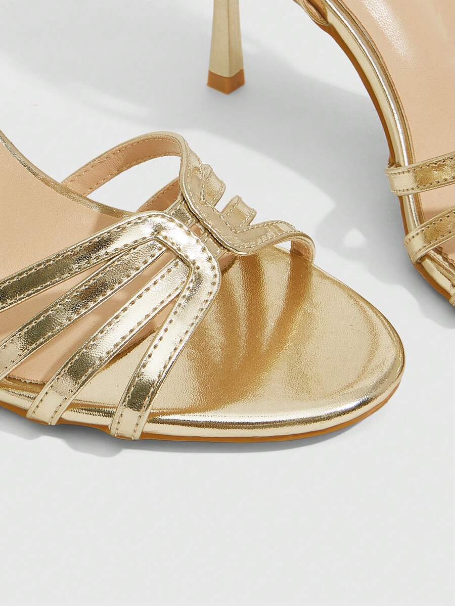 Women's champagne stiletto high heel sandals featuring knotted cross-over straps, open round toe, and adjustable ankle buckle strap.