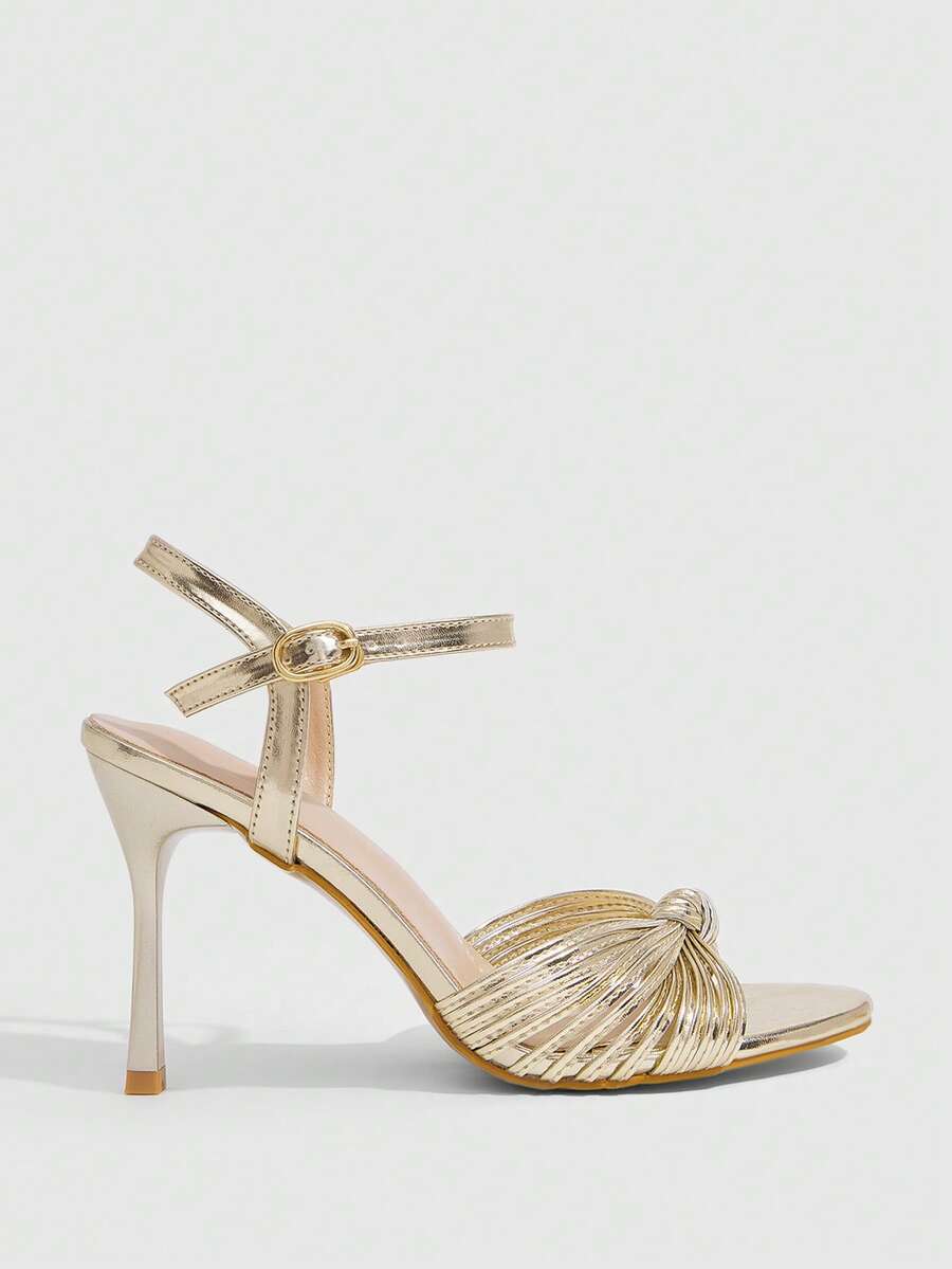 Women's champagne stiletto high heel sandals featuring knotted cross-over straps, open round toe, and adjustable ankle buckle strap.