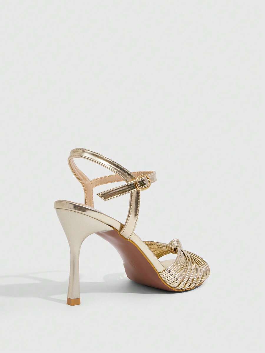 Women's champagne stiletto high heel sandals featuring knotted cross-over straps, open round toe, and adjustable ankle buckle strap.