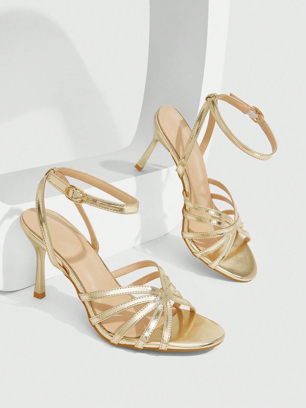 Women's champagne stiletto high heel sandals featuring knotted cross-over straps, open round toe, and adjustable ankle buckle strap.