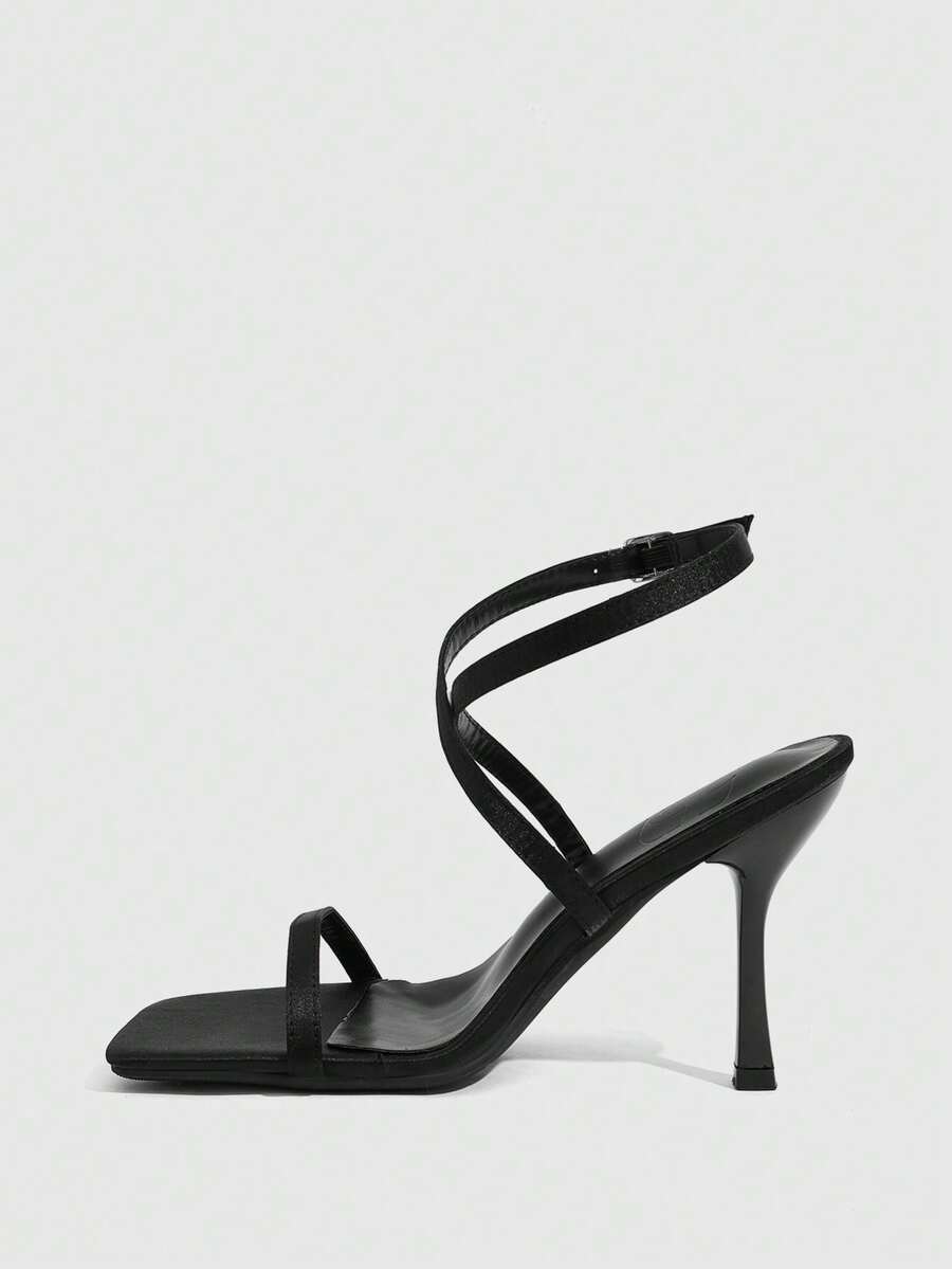 Pair of women's brown satin open toe stiletto sandals with cross ankle buckle straps.