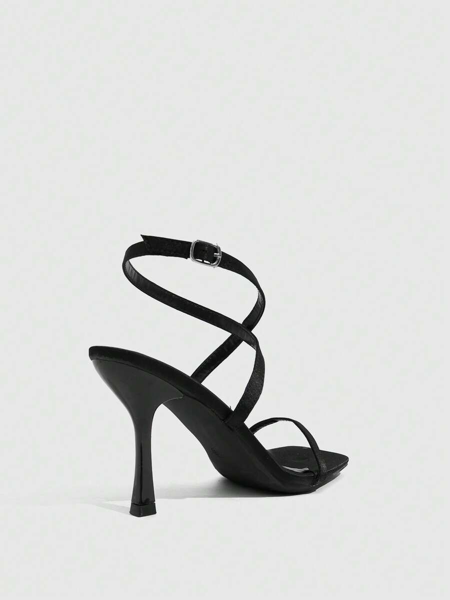 Pair of women's brown satin open toe stiletto sandals with cross ankle buckle straps.