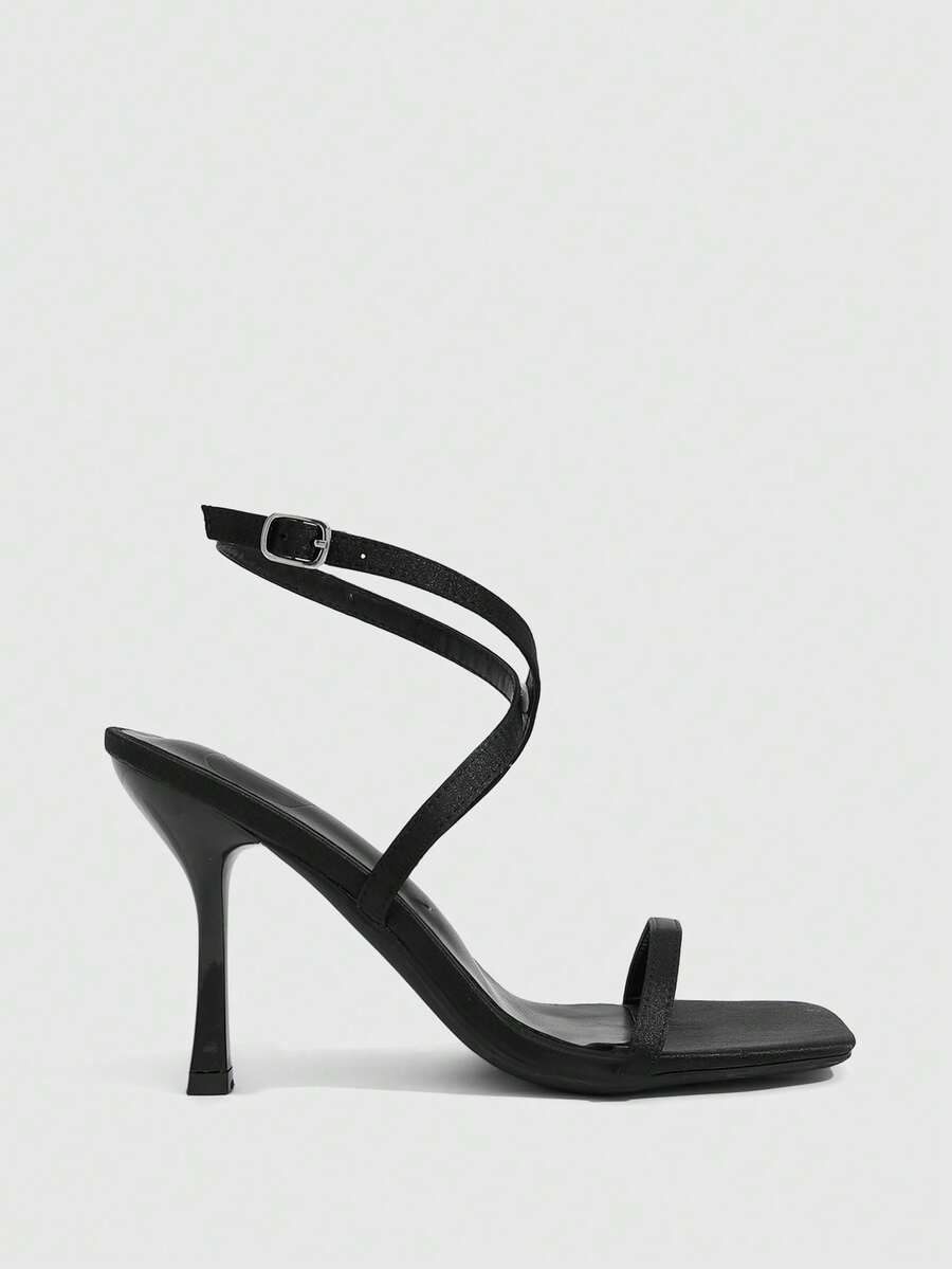 Pair of women's brown satin open toe stiletto sandals with cross ankle buckle straps.