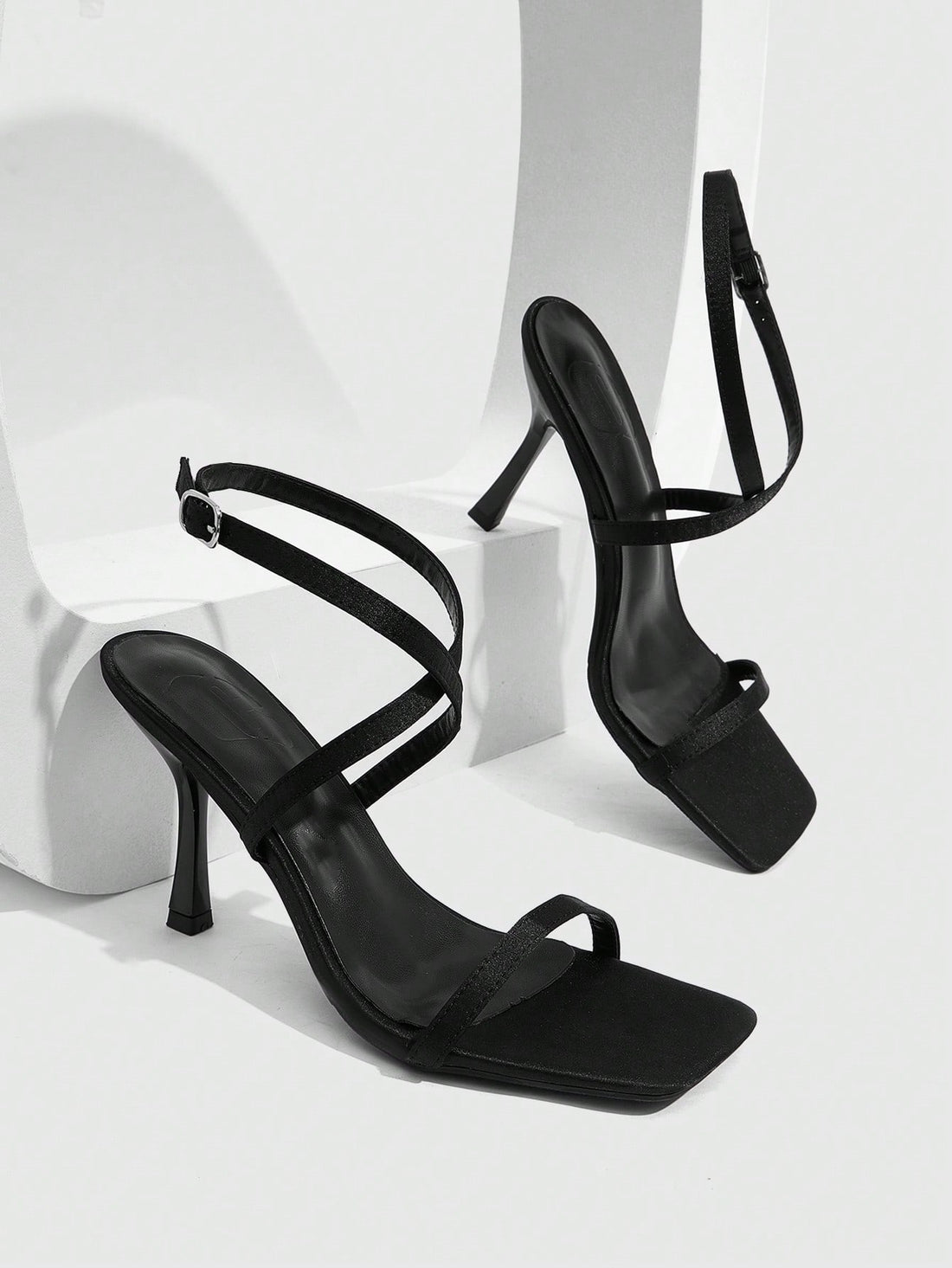 Pair of women's brown satin open toe stiletto sandals with cross ankle buckle straps.