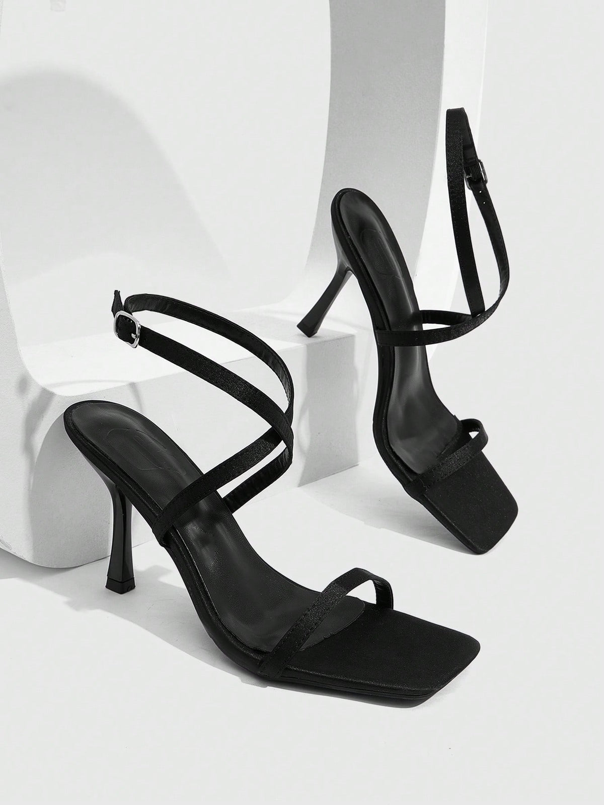 Pair of women's brown satin open toe stiletto sandals with cross ankle buckle straps.