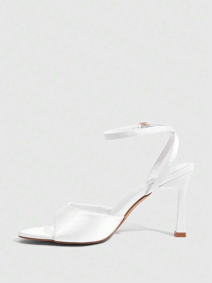 Women's pointed peep toe high heel stilettos featuring cross ankle strap with buckle in black PU leather.