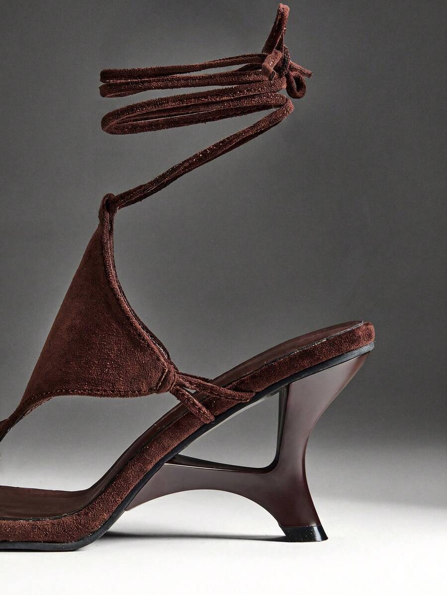 Chocolate brown women's lace-up leg wrap sculpted wedge thong sandals with strappy rope ties and textured high heel.