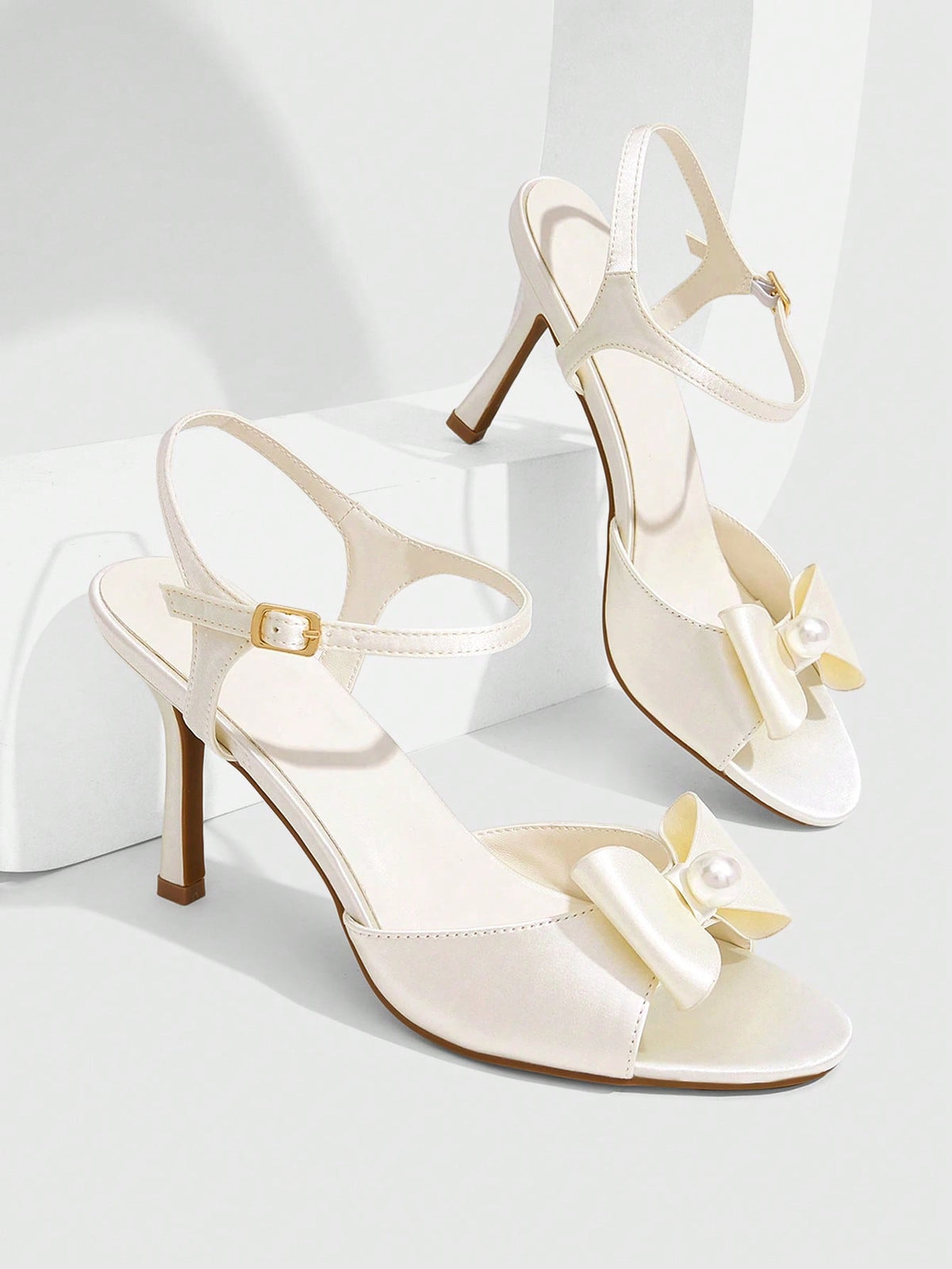 Elegant women's satin high heel sandals with pearl embellishments, stiletto heels, and slingback straps for bridal and wedding wear.