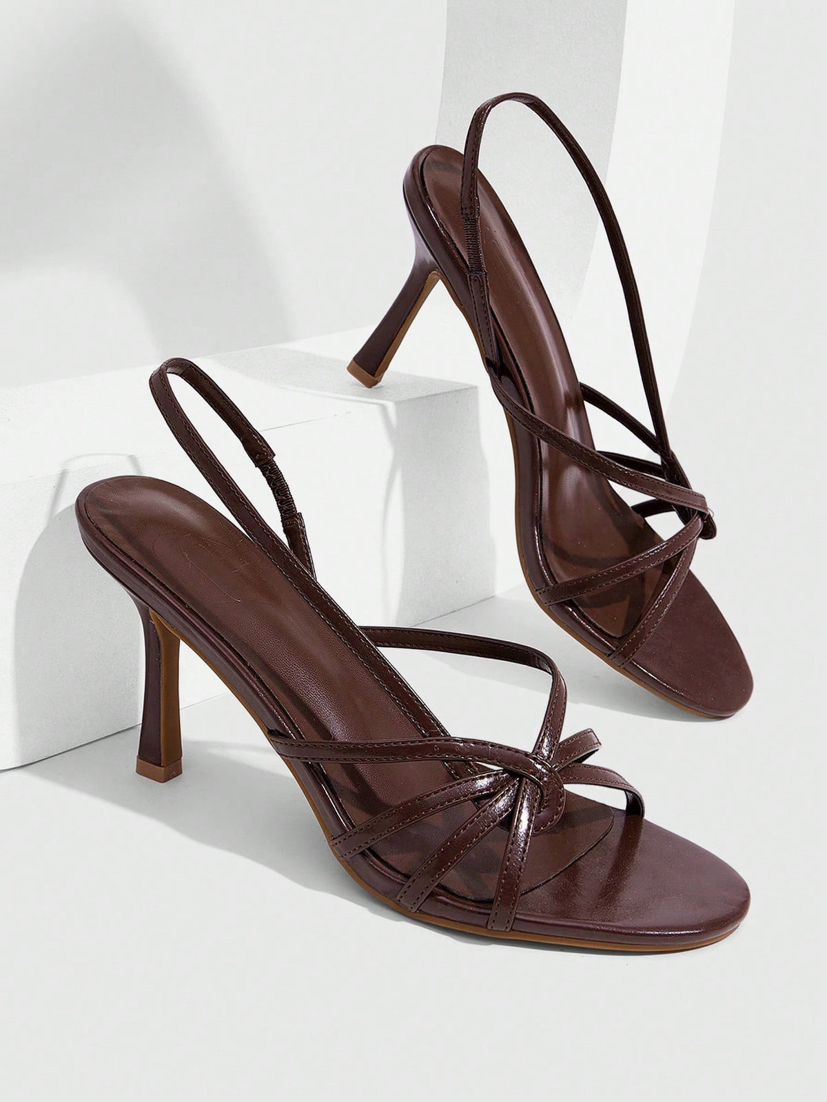 Women's high heel sandals featuring pleated strap detailing, an adjustable ankle strap with buckle closure, round open toe, and slim stiletto heel.