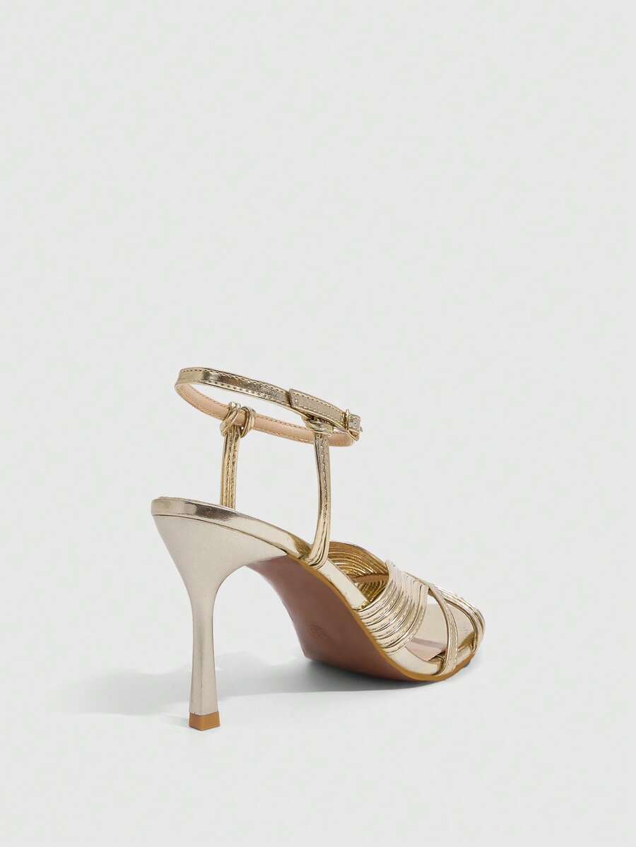 Women's champagne stiletto high heel sandals featuring knotted cross-over straps, open round toe, and adjustable ankle buckle strap.