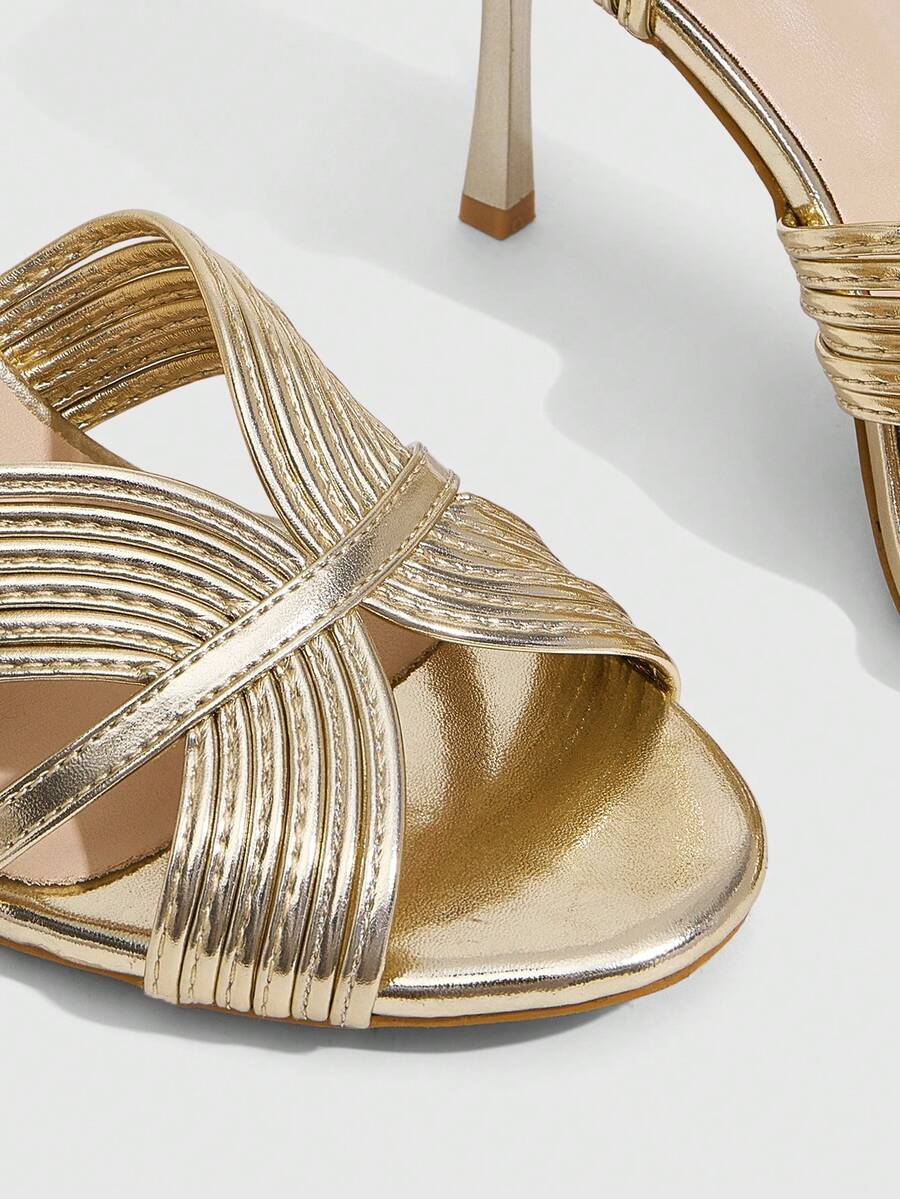 Women's champagne stiletto high heel sandals featuring knotted cross-over straps, open round toe, and adjustable ankle buckle strap.