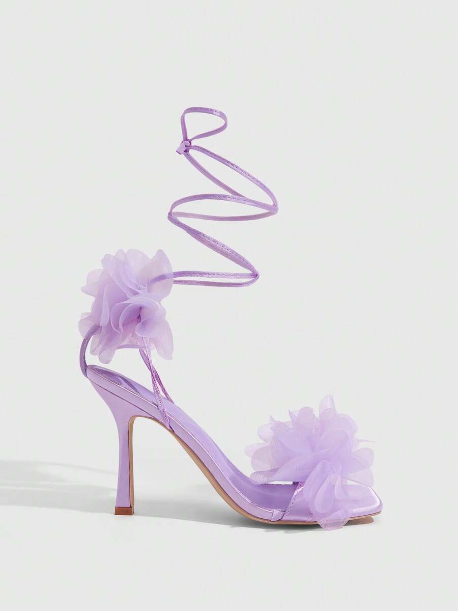 Women's open toe heeled sandals featuring 3D floral decor, satin lace-up ankle straps, and stiletto high heels.
