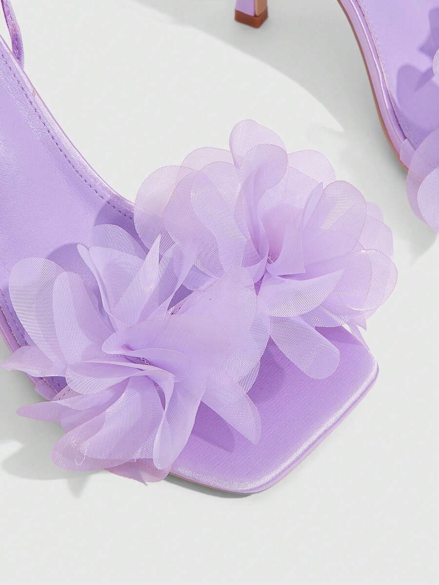 Women's open toe heeled sandals featuring 3D floral decor, satin lace-up ankle straps, and stiletto high heels.