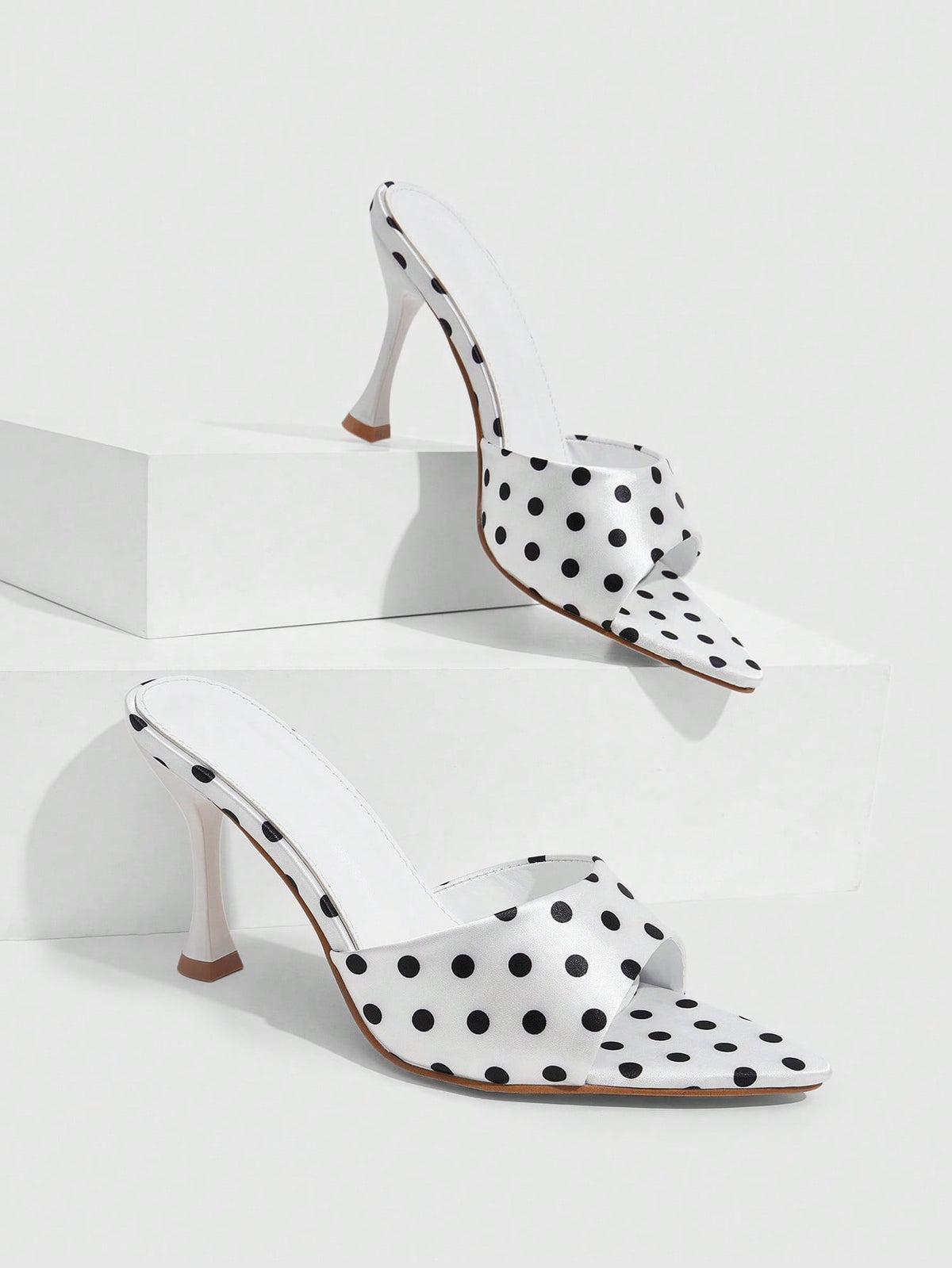 Pair of women's pointed toe stiletto mule sandals with shiny patent upper and slip-on design.