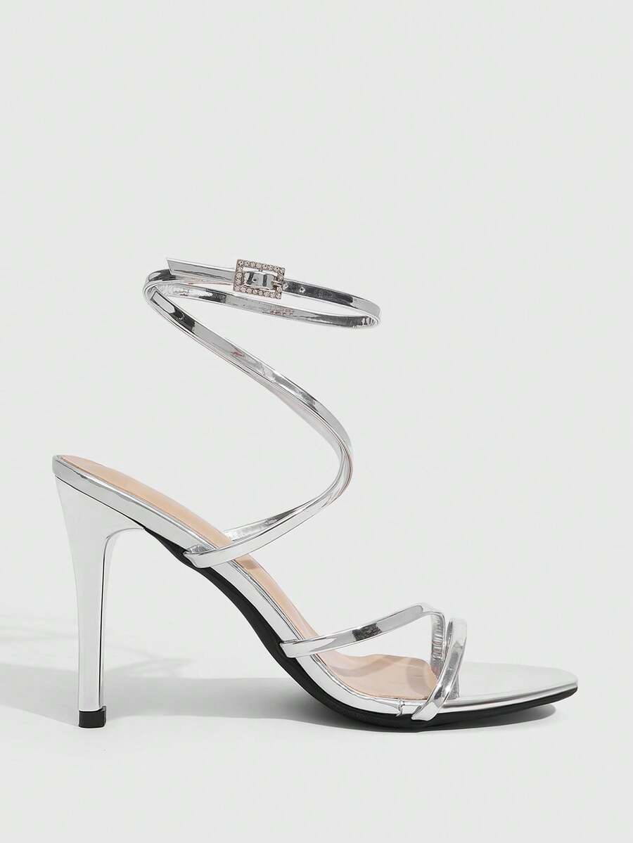 Silver high-heeled sandals featuring a rhinestone buckle ankle strap and sleek stiletto heel.