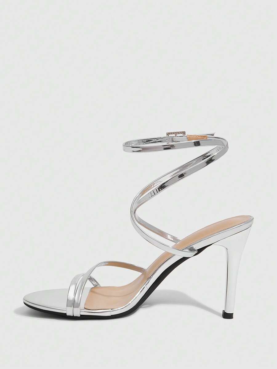 Silver high-heeled sandals featuring a rhinestone buckle ankle strap and sleek stiletto heel.