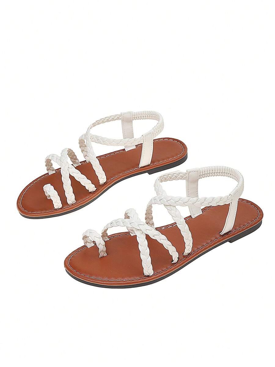 Flat sandals featuring thin criss-cross straps, elastic back strap, round toe post design, and smooth flat rubber sole.