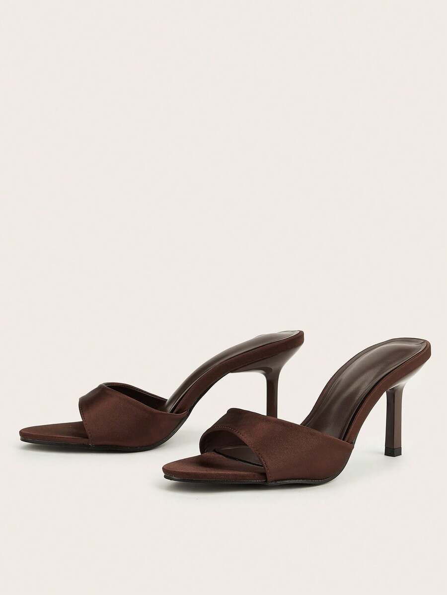 Brown cow print and polka dot stiletto high heel sandals with an open peep toe, satin upper, and buckle accent.