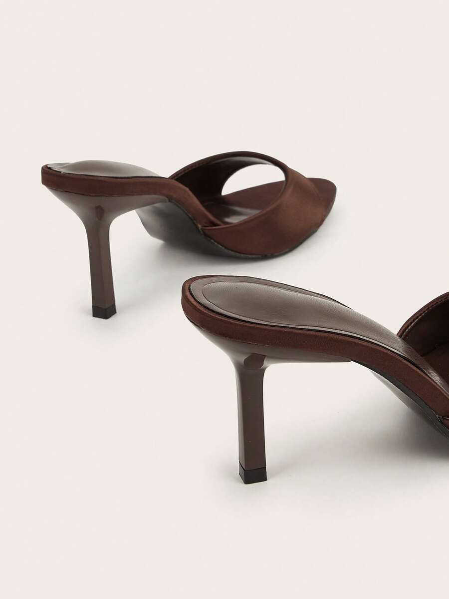 Brown cow print and polka dot stiletto high heel sandals with an open peep toe, satin upper, and buckle accent.