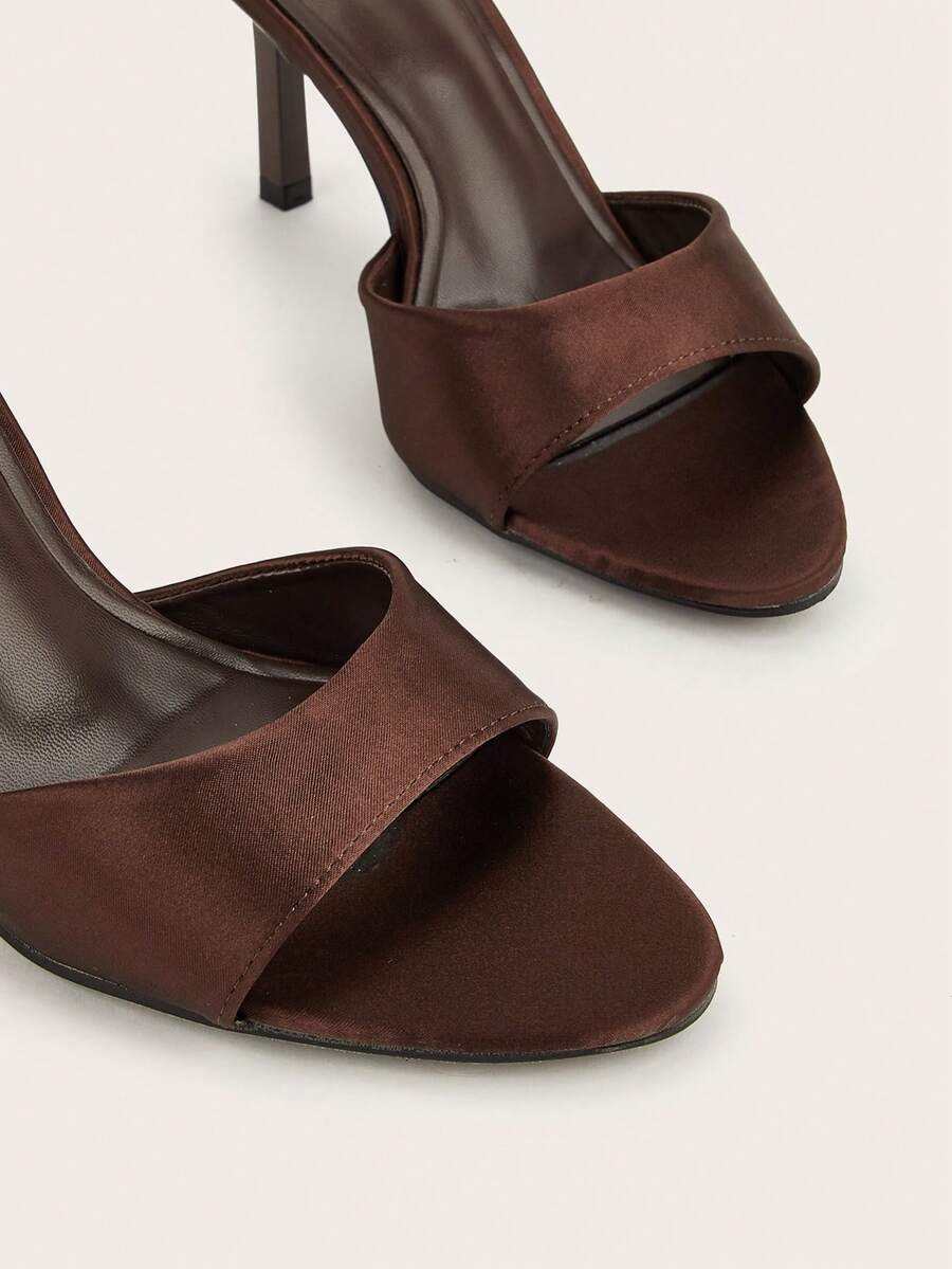 Brown cow print and polka dot stiletto high heel sandals with an open peep toe, satin upper, and buckle accent.