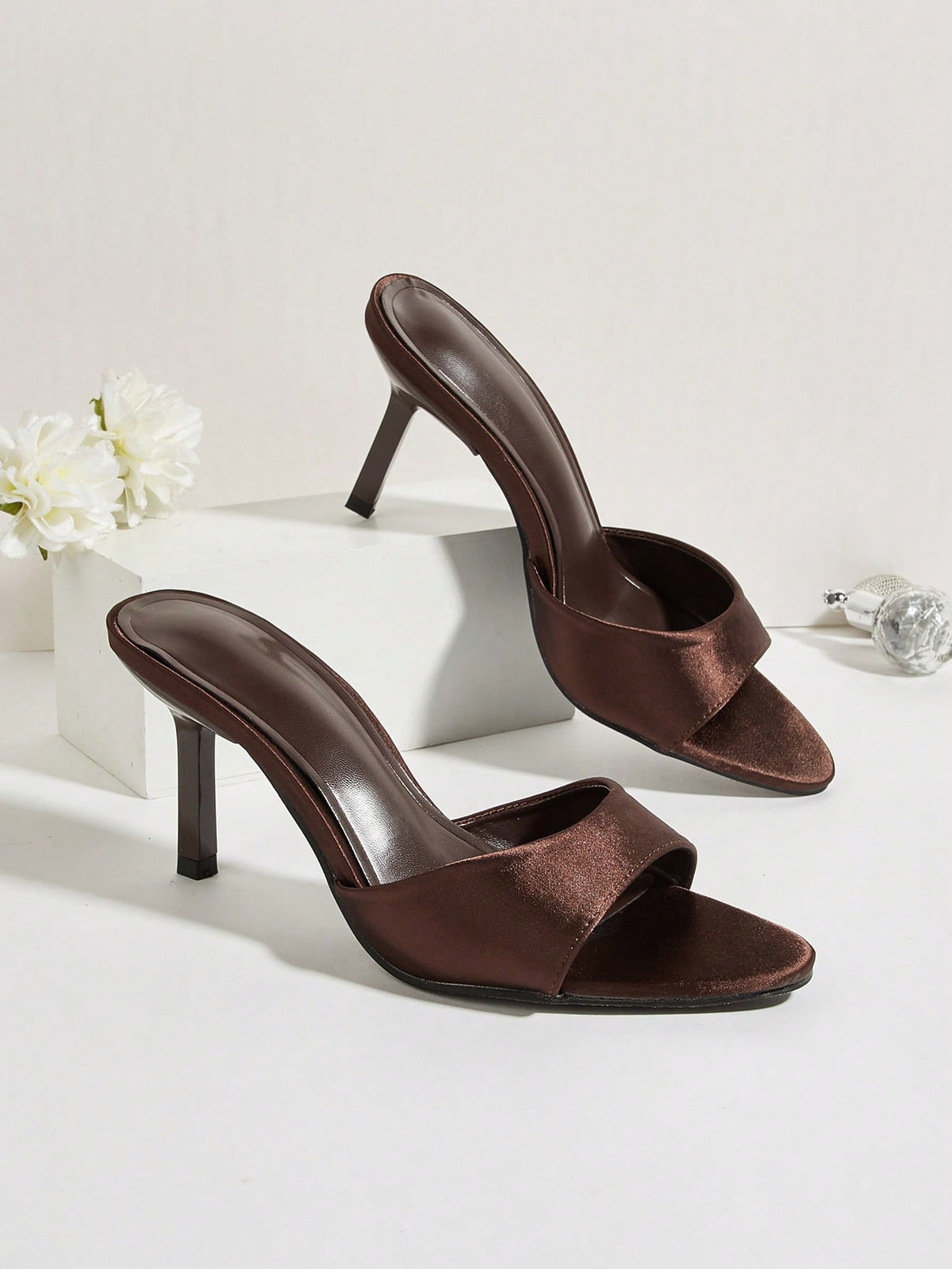 Brown cow print and polka dot stiletto high heel sandals with an open peep toe, satin upper, and buckle accent.