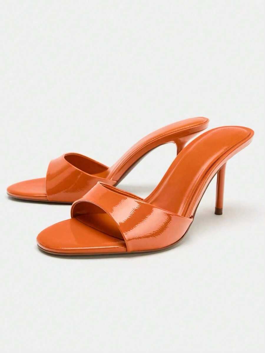 Pair of women's open toe patent leather mule shoes with sleek stiletto heels and cut-out styling
