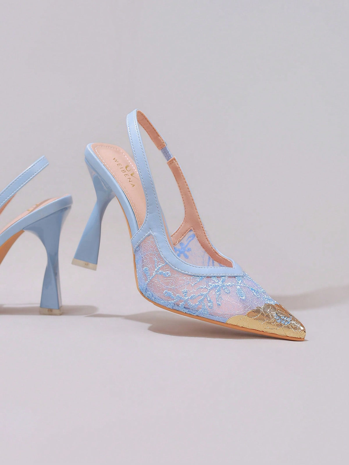Lace embroidered high heels with thin stiletto heel, pointed toe, rhinestone embellishments, and ankle strap buckle closure.
