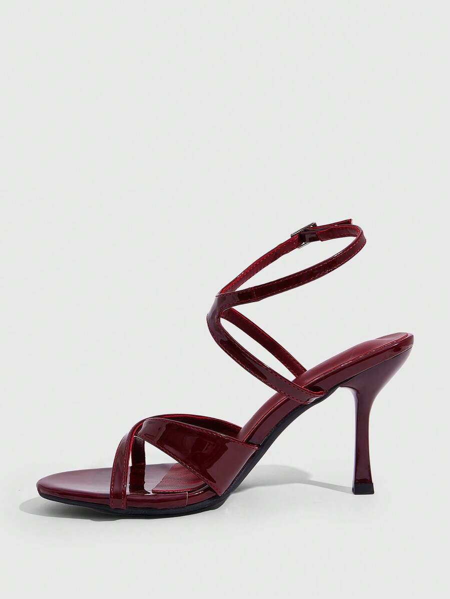 Women's glossy patent leather stiletto sandals in burgundy with open toe design and buckle strap closure.