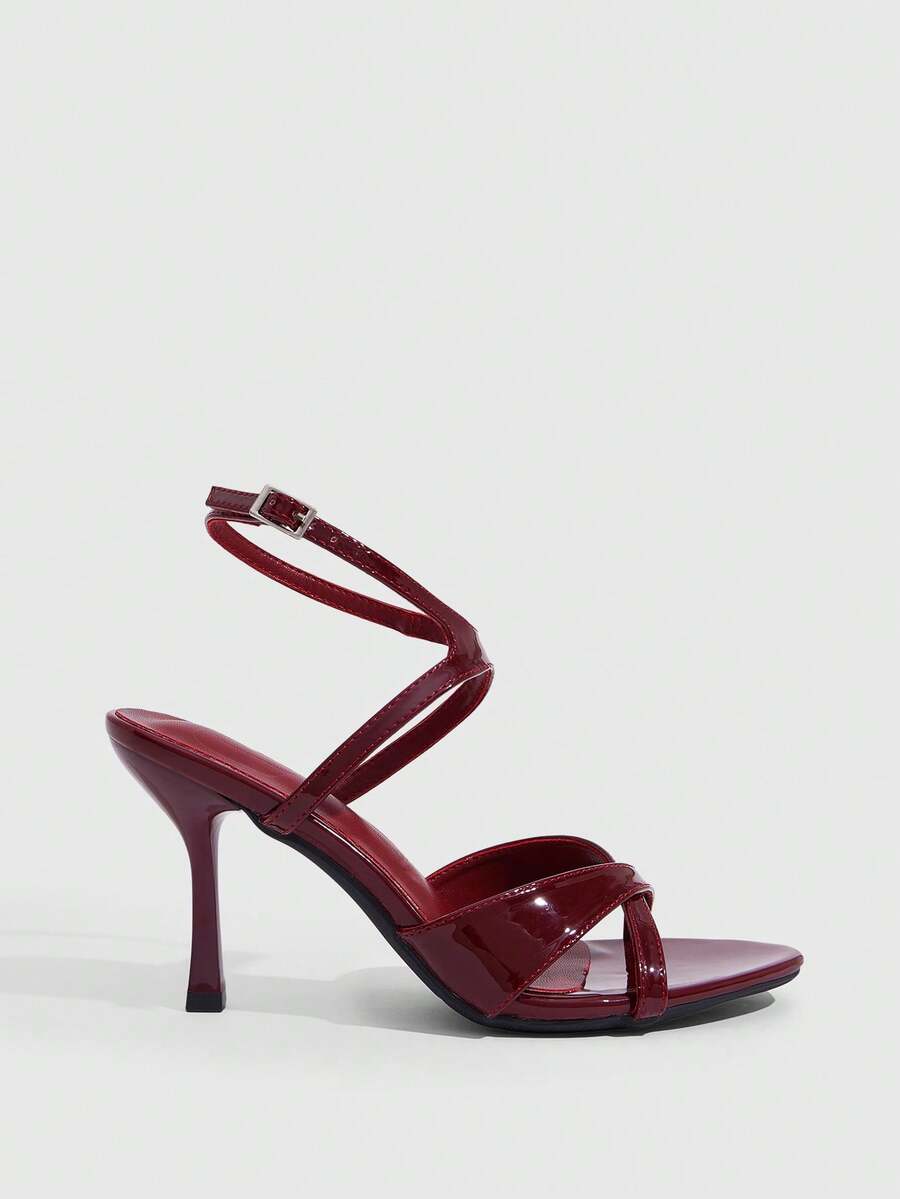 Women's glossy patent leather stiletto sandals in burgundy with open toe design and buckle strap closure.