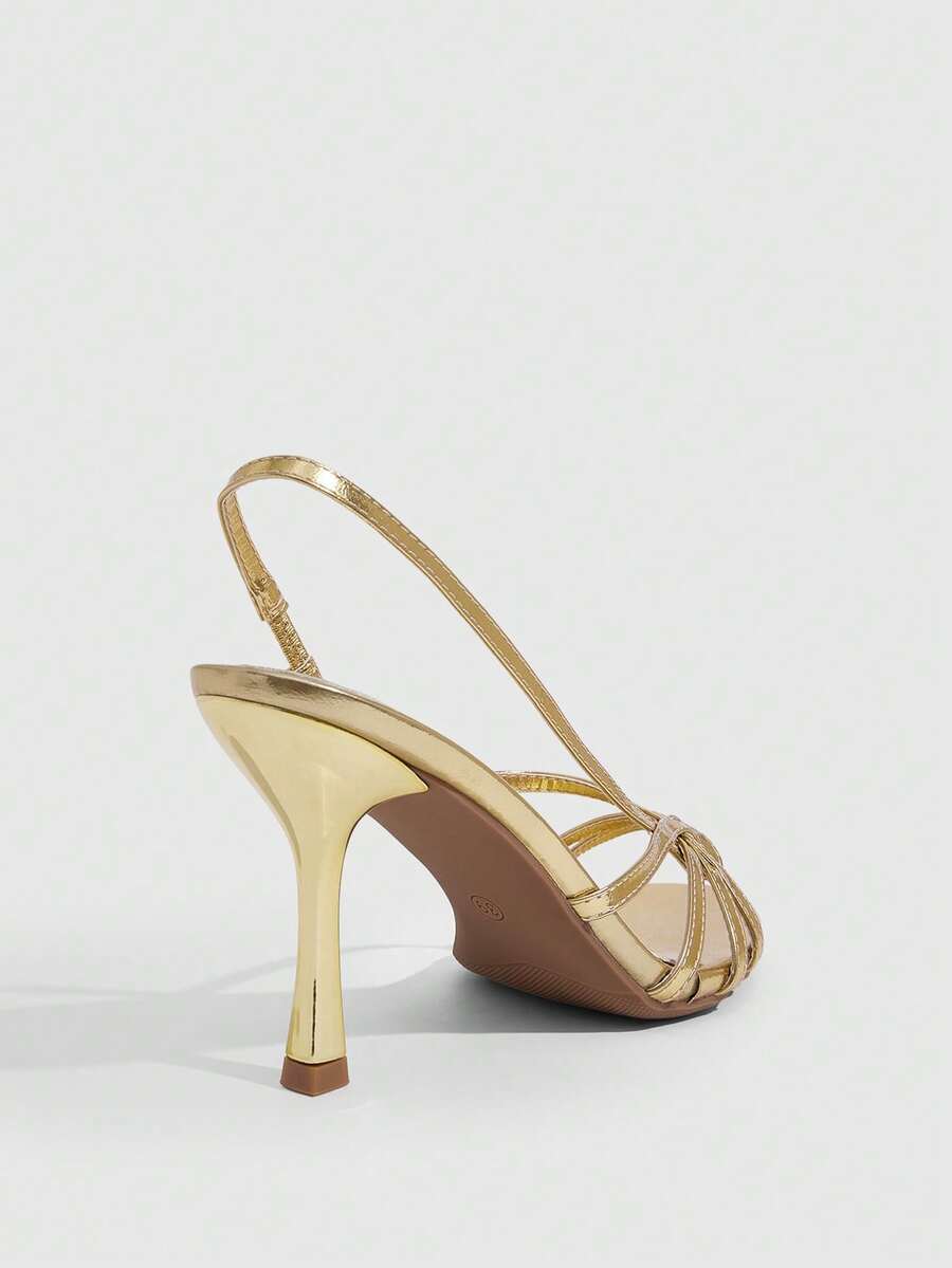 Women's open-toed stiletto high-heeled sandals in glossy patent black featuring twist strap detailing and slingback design.