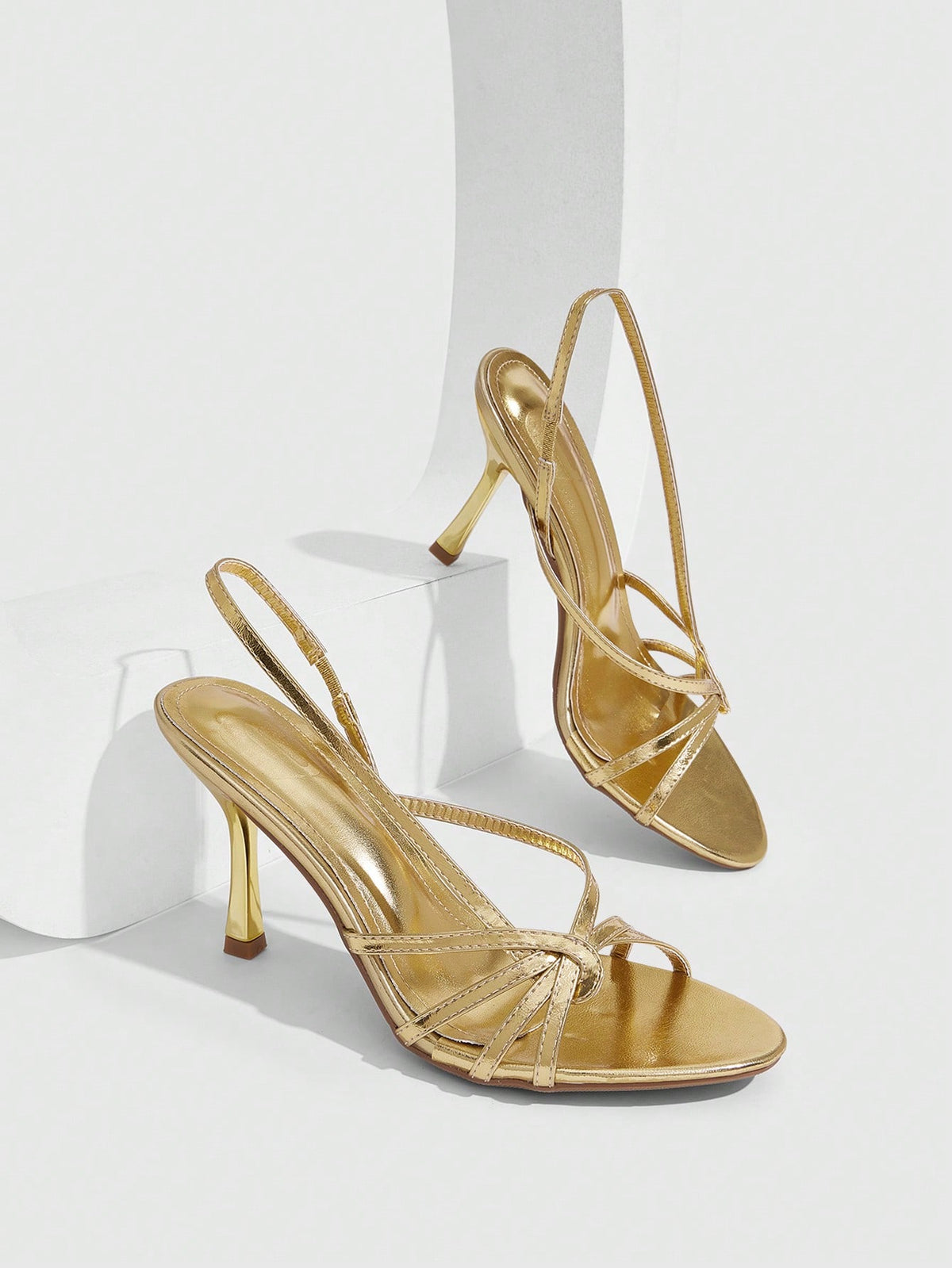 Women's open-toed stiletto high-heeled sandals in glossy patent black featuring twist strap detailing and slingback design.