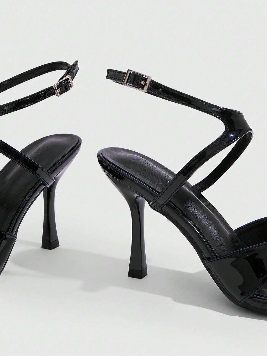 Women's glossy patent leather stiletto sandals in burgundy with open toe design and buckle strap closure.
