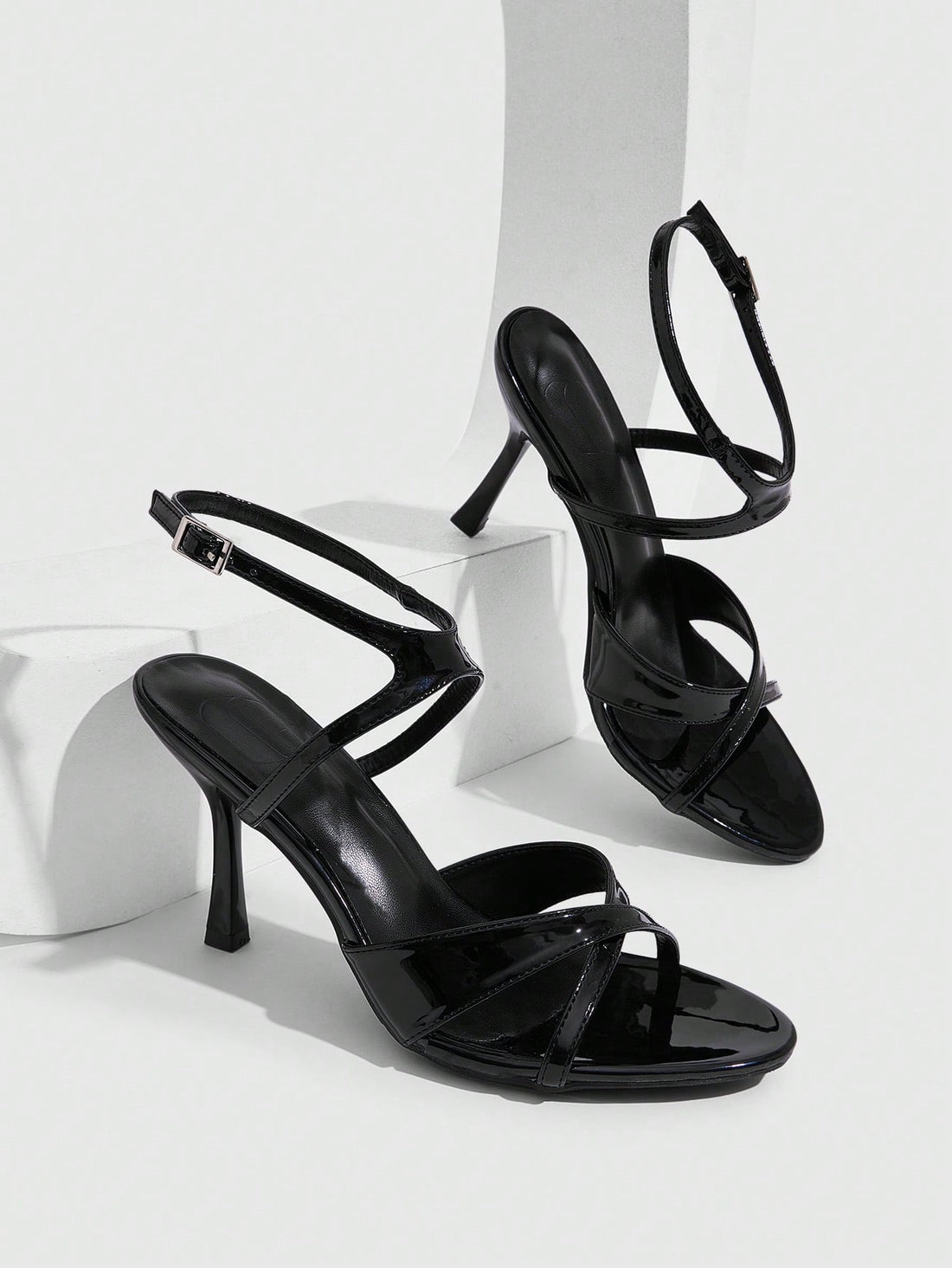 Women's glossy patent leather stiletto sandals in burgundy with open toe design and buckle strap closure.