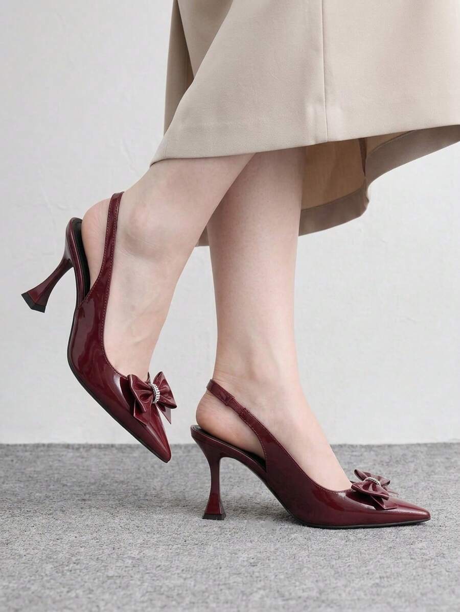 Women's pointed-toe high heel pumps in black mirror PU leather with an ankle strap, stiletto heel, and rhinestone buckle.