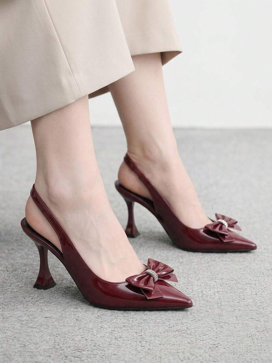 Women's pointed-toe high heel pumps in black mirror PU leather with an ankle strap, stiletto heel, and rhinestone buckle.