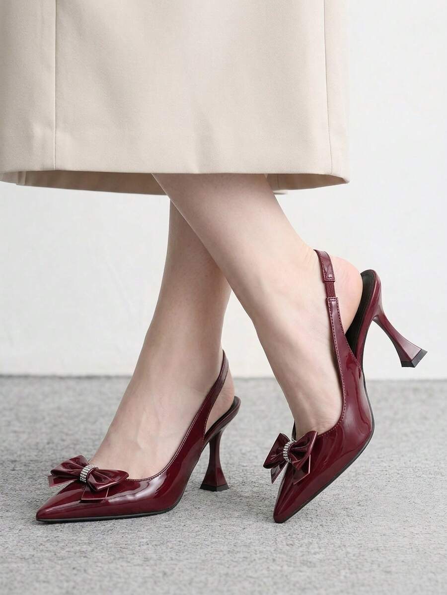 Women's pointed-toe high heel pumps in black mirror PU leather with an ankle strap, stiletto heel, and rhinestone buckle.