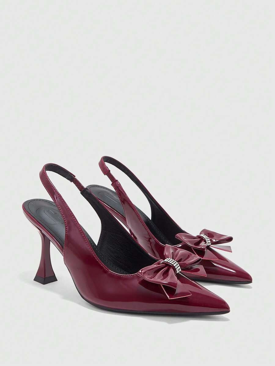 Women's pointed-toe high heel pumps in black mirror PU leather with an ankle strap, stiletto heel, and rhinestone buckle.
