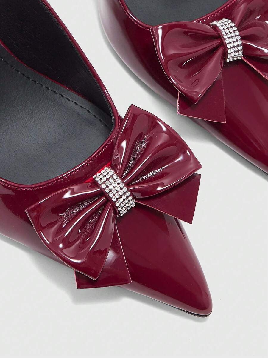 Women's pointed-toe high heel pumps in black mirror PU leather with an ankle strap, stiletto heel, and rhinestone buckle.