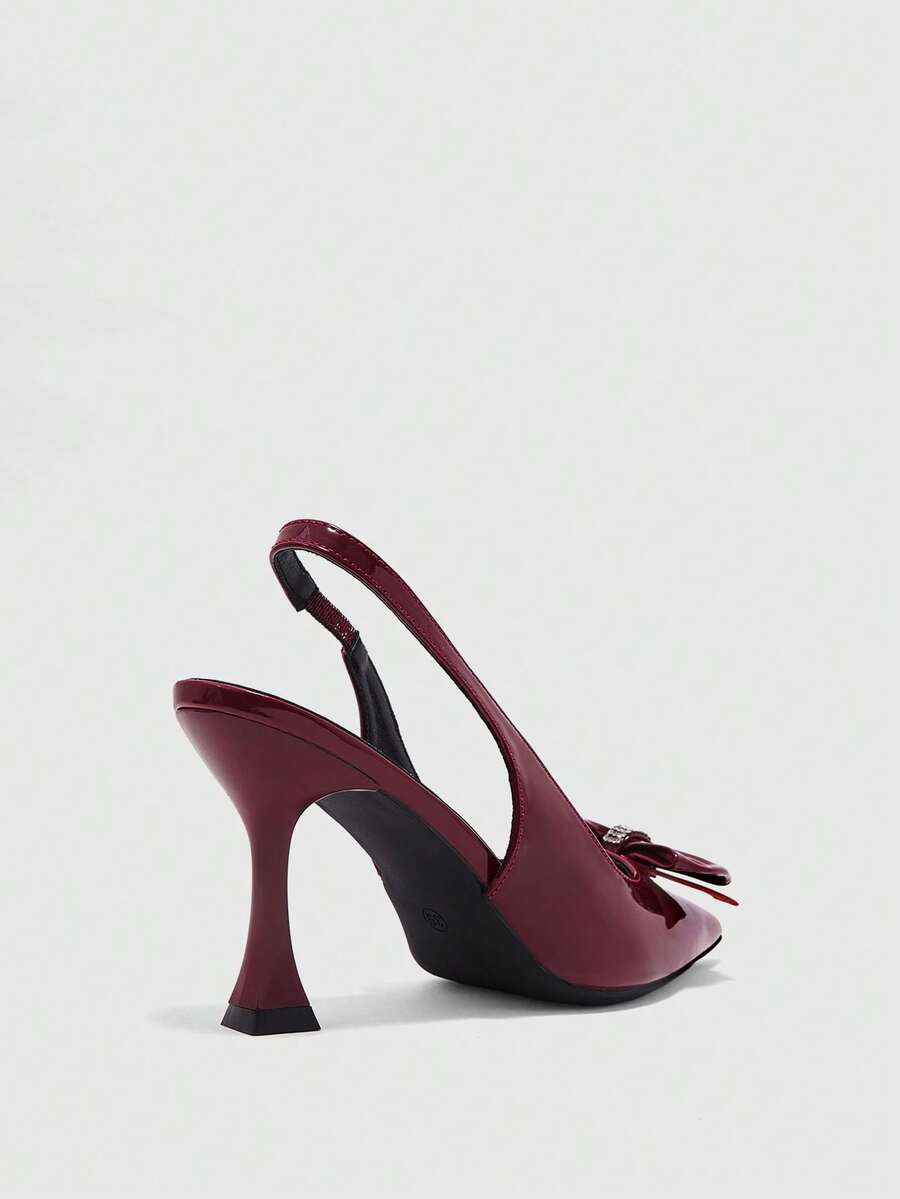 Women's pointed-toe high heel pumps in black mirror PU leather with an ankle strap, stiletto heel, and rhinestone buckle.