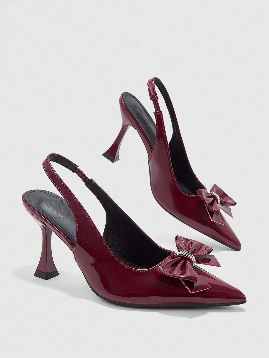 Women's pointed-toe high heel pumps in black mirror PU leather with an ankle strap, stiletto heel, and rhinestone buckle.