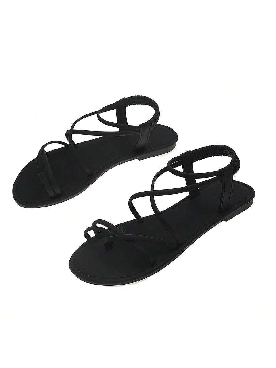 Flat sandals featuring thin criss-cross straps, elastic back strap, round toe post design, and smooth flat rubber sole.