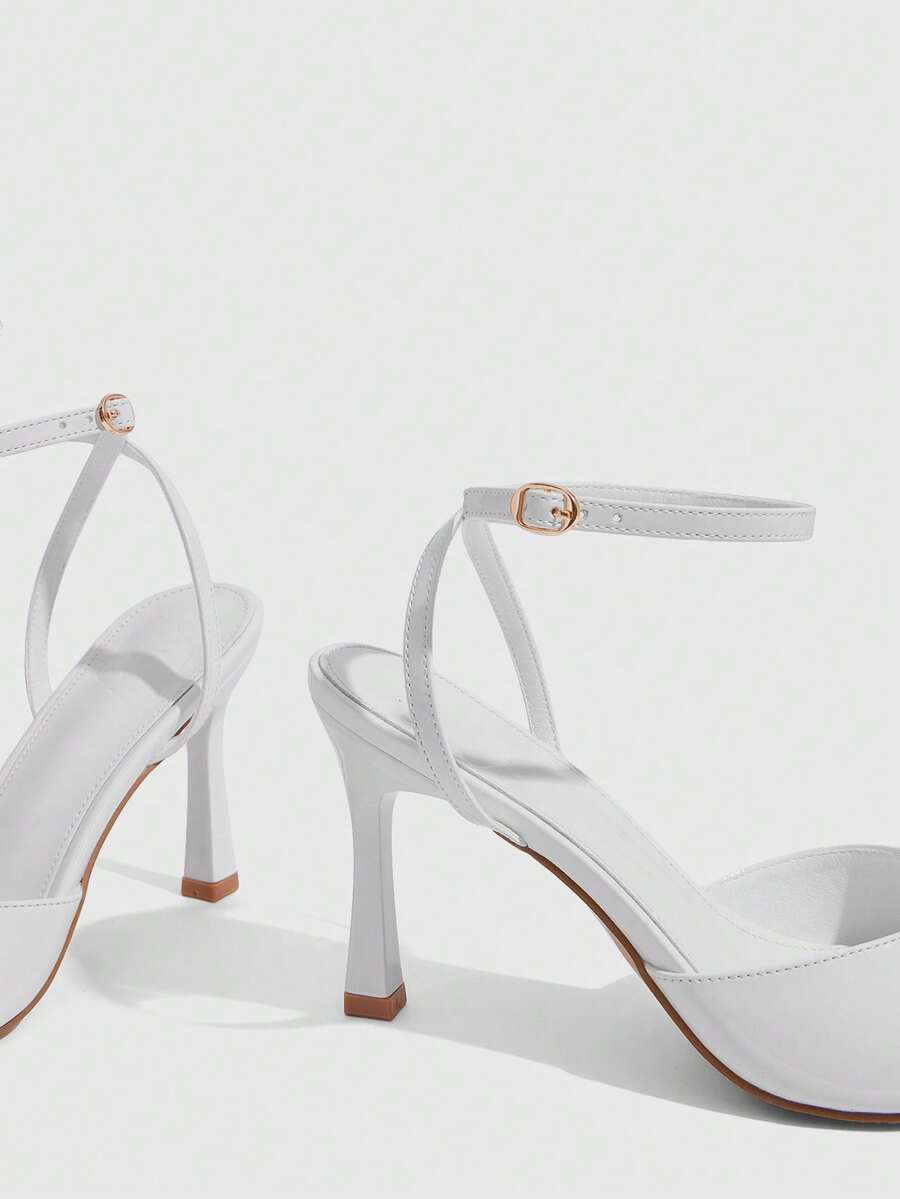 Women's pointed peep toe high heel stilettos featuring cross ankle strap with buckle in black PU leather.