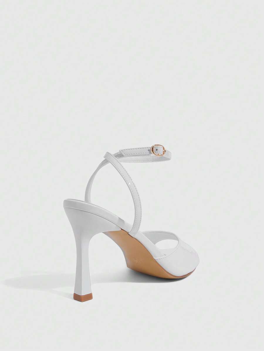 Women's pointed peep toe high heel stilettos featuring cross ankle strap with buckle in black PU leather.