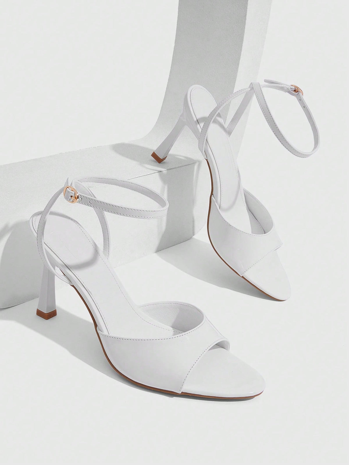 Women's pointed peep toe high heel stilettos featuring cross ankle strap with buckle in black PU leather.