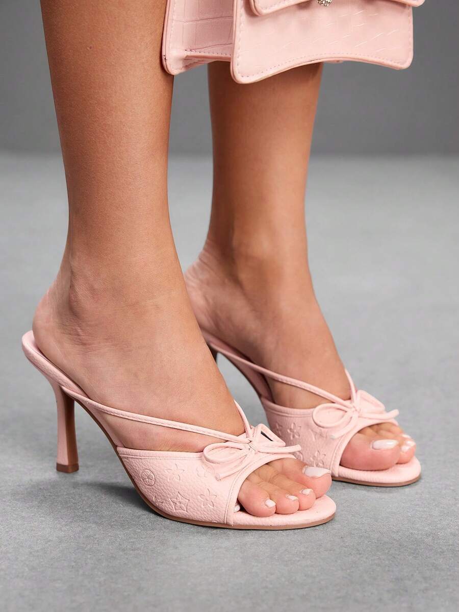 Elegant high heel sandals with romantic bow strap and slim stiletto heel for party and wedding occasions.
